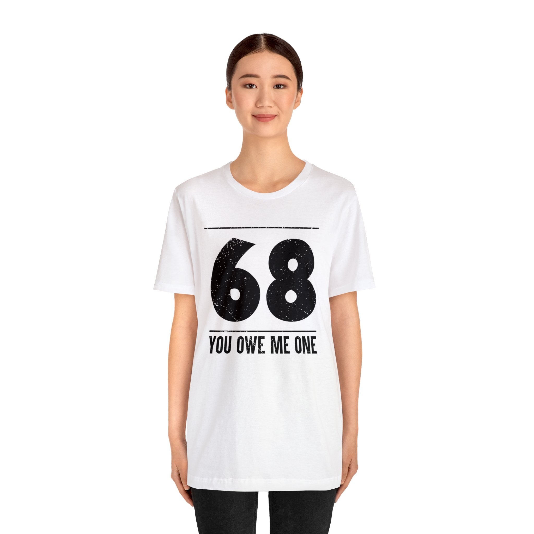 A woman wearing a geeky white t-shirt that says 68 You Owe Me One.