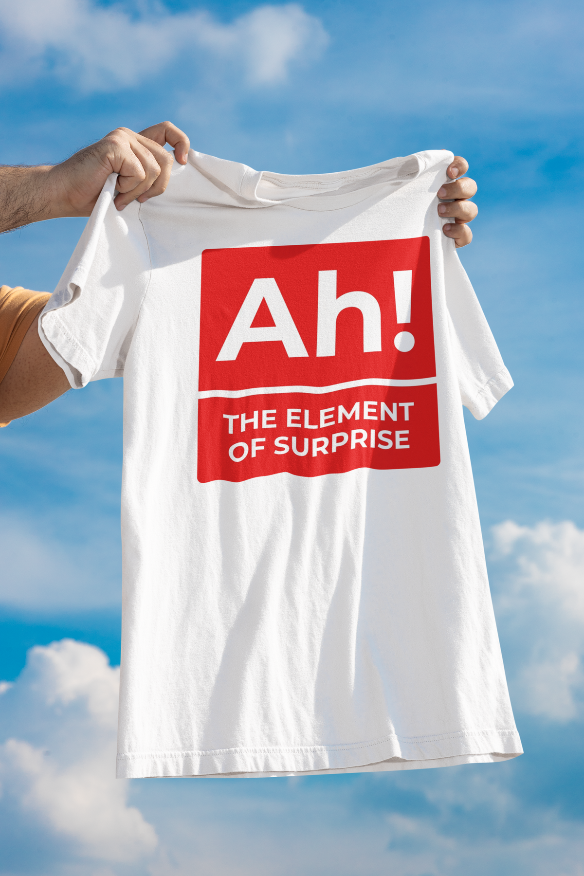 'Ah! The Element of Surprise' T-shirt in white, held up outdoors against a blue sky, science gift