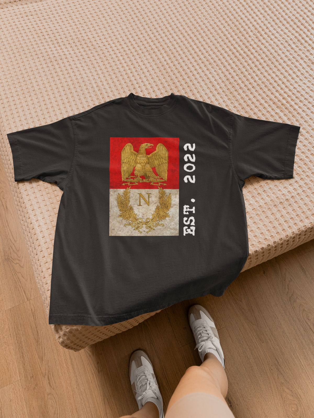 'Listenbourg Est. 2022' eagle crest t-shirt in black, flat lay on a bed