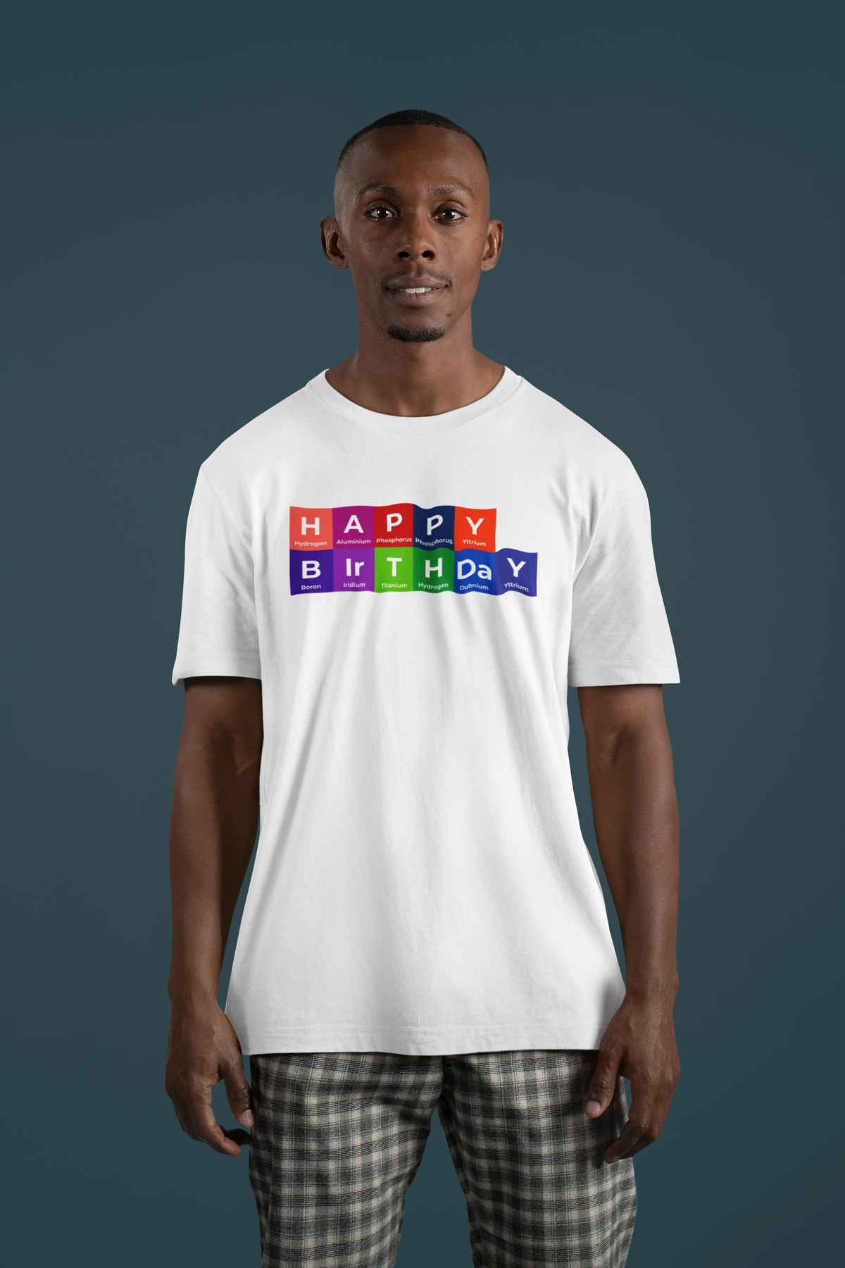 'Happy Birthday' periodic table t-shirt in white, man wearing it on a dark teal background, funny tee