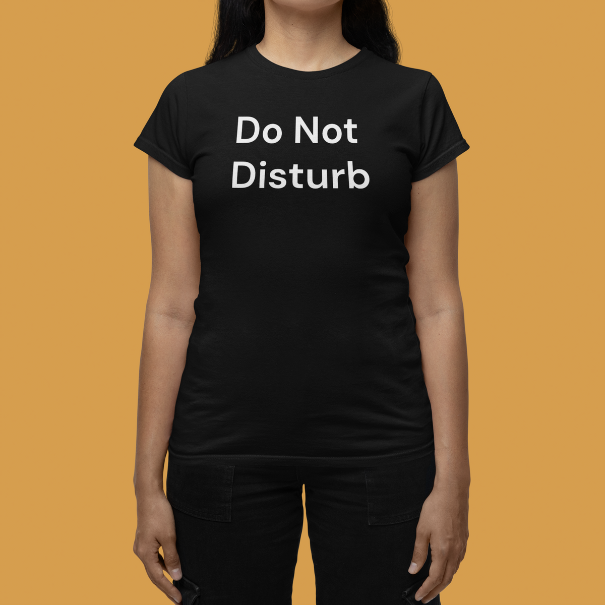 'Do Not Disturb' women's tee in black, woman wearing it against a yellow backdrop, funny statement tee gift