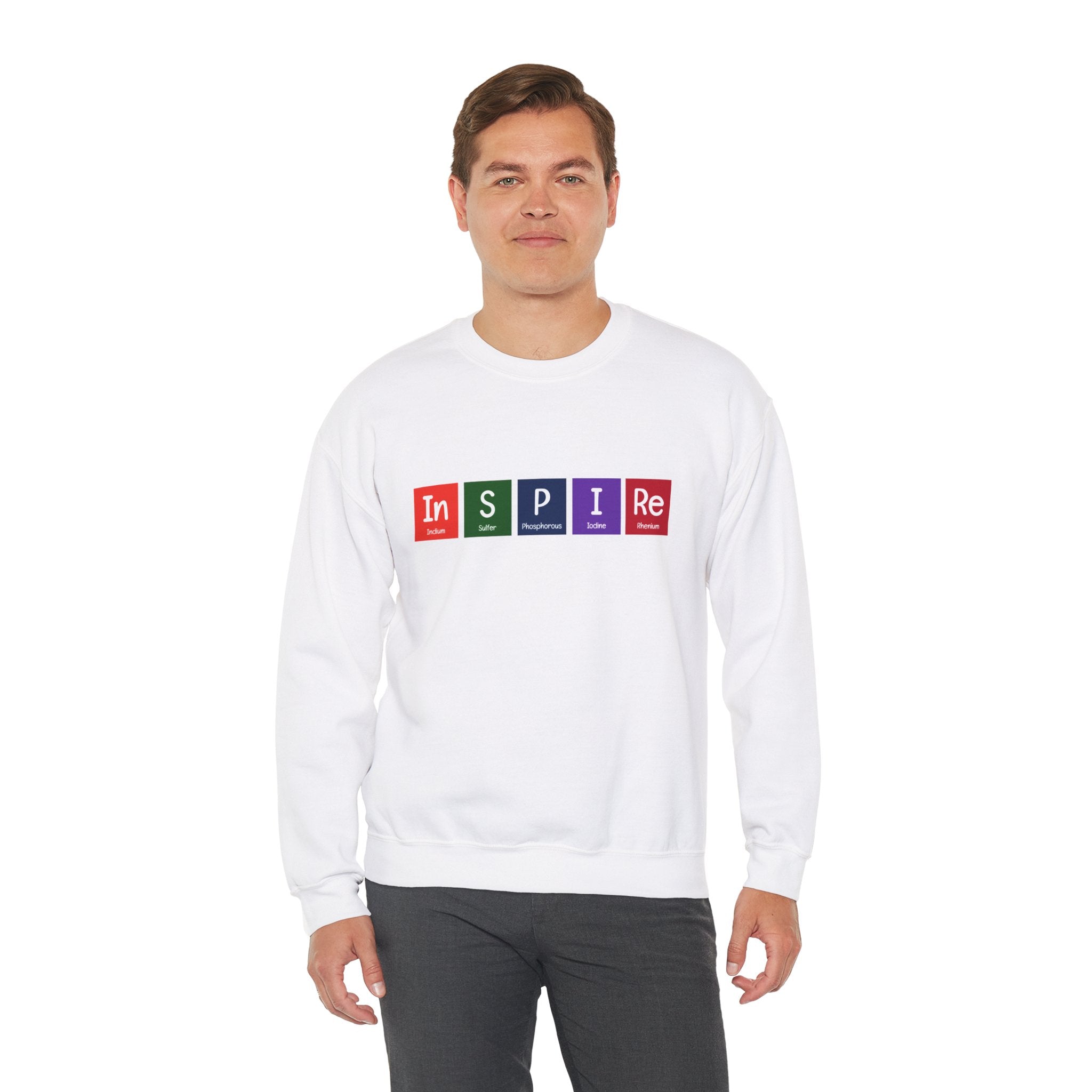A man, standing against a plain white background, is wearing a cozy In-S-P-I-Re - Sweatshirt perfect for the colder months. The white sweatshirt features the word "INSPIRE" written using elements from the periodic table.