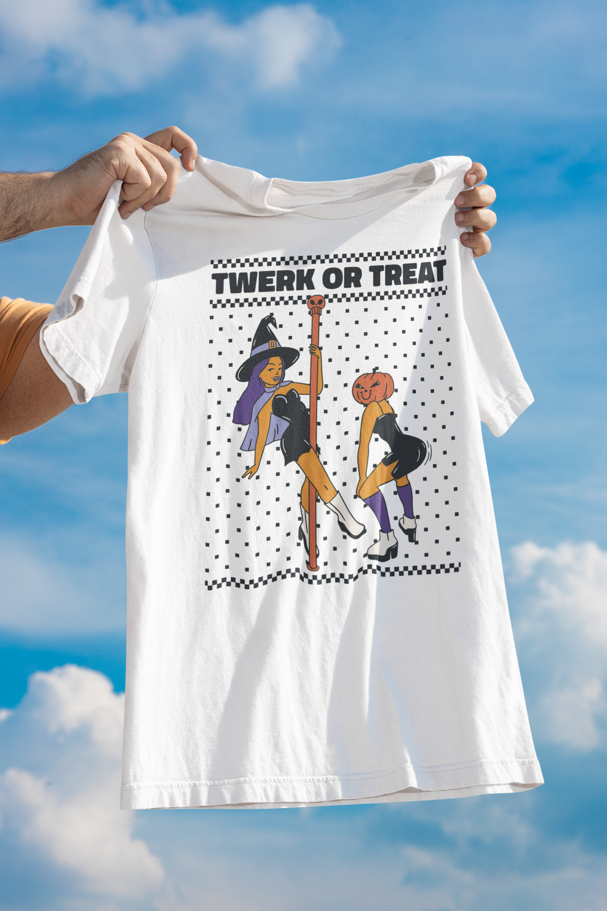 'Twerk Or Treat' t-shirt in white, held up against a cloudy sky backdrop, funny spooky season tee