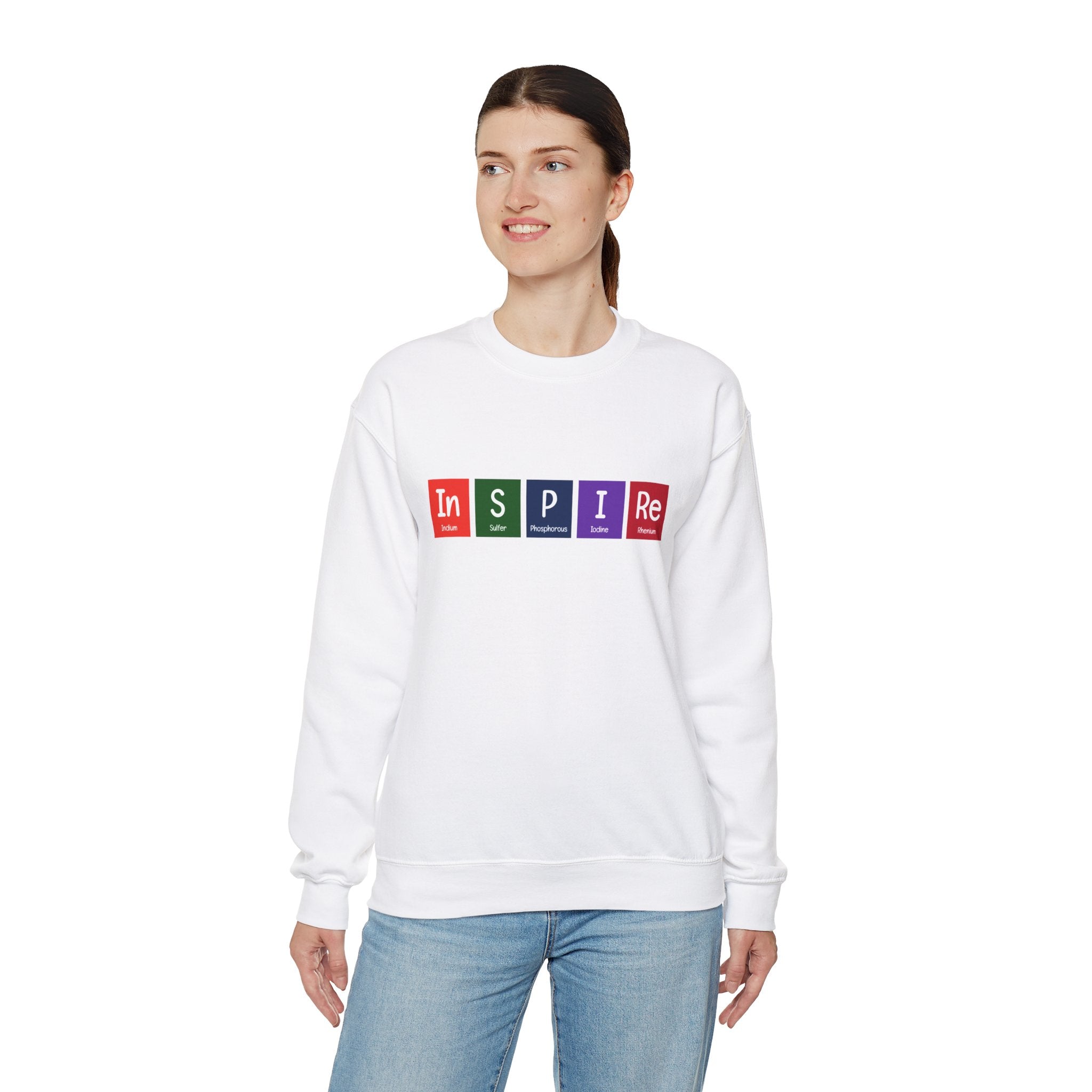 A person wearing a cozy white In-S-P-I-Re - Sweatshirt with the word "INSPIRE" written in colorful block letters, standing and looking to the side. Perfect for the colder months ahead, this ensemble radiates warmth and inspiration.