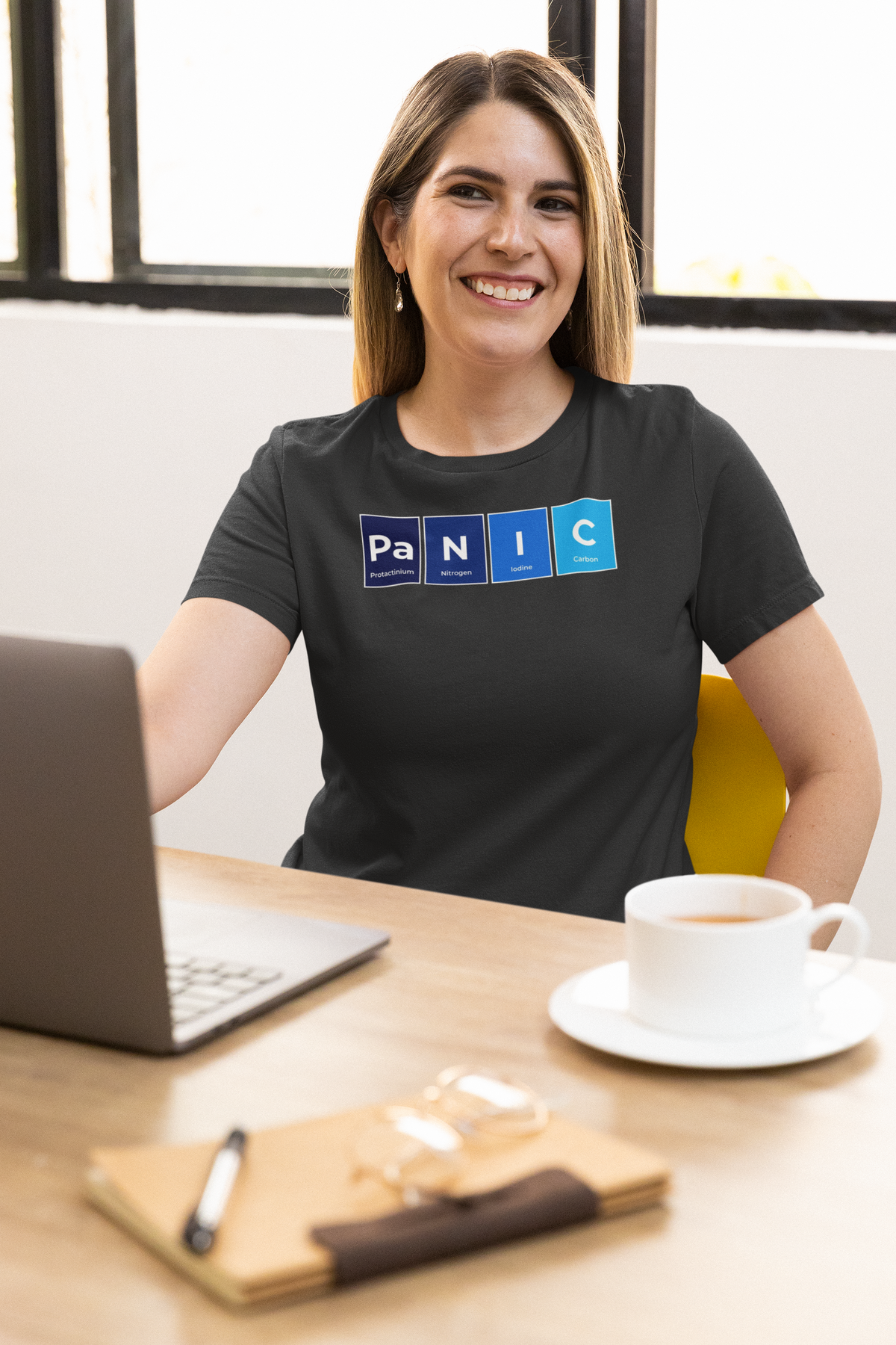 'Pa-N-I-C' periodic table t-shirt in black, smiling woman wearing it at a desk, office lifestyle photo