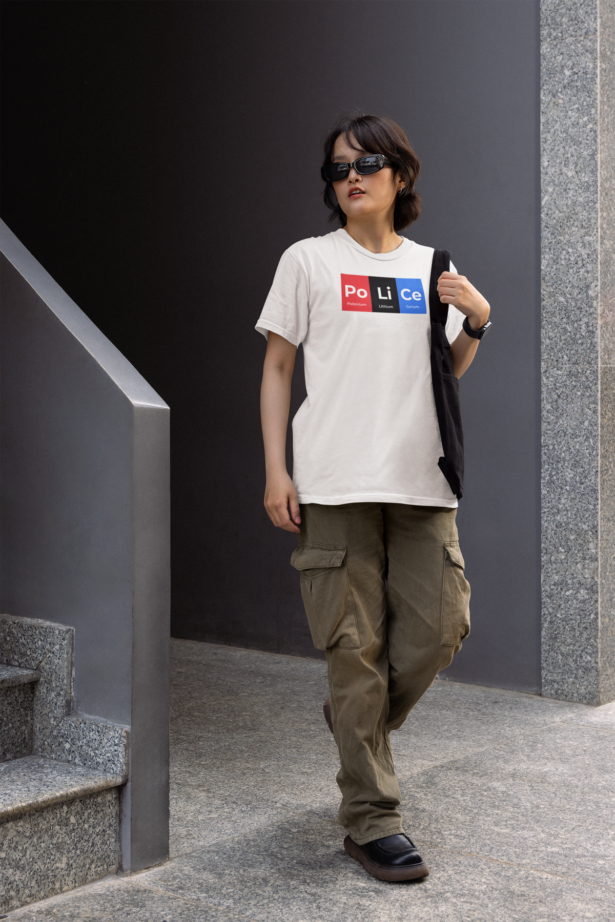 'Po-Li-Ce' periodic table women's tee in white, woman walking outdoors, casual streetwear photo