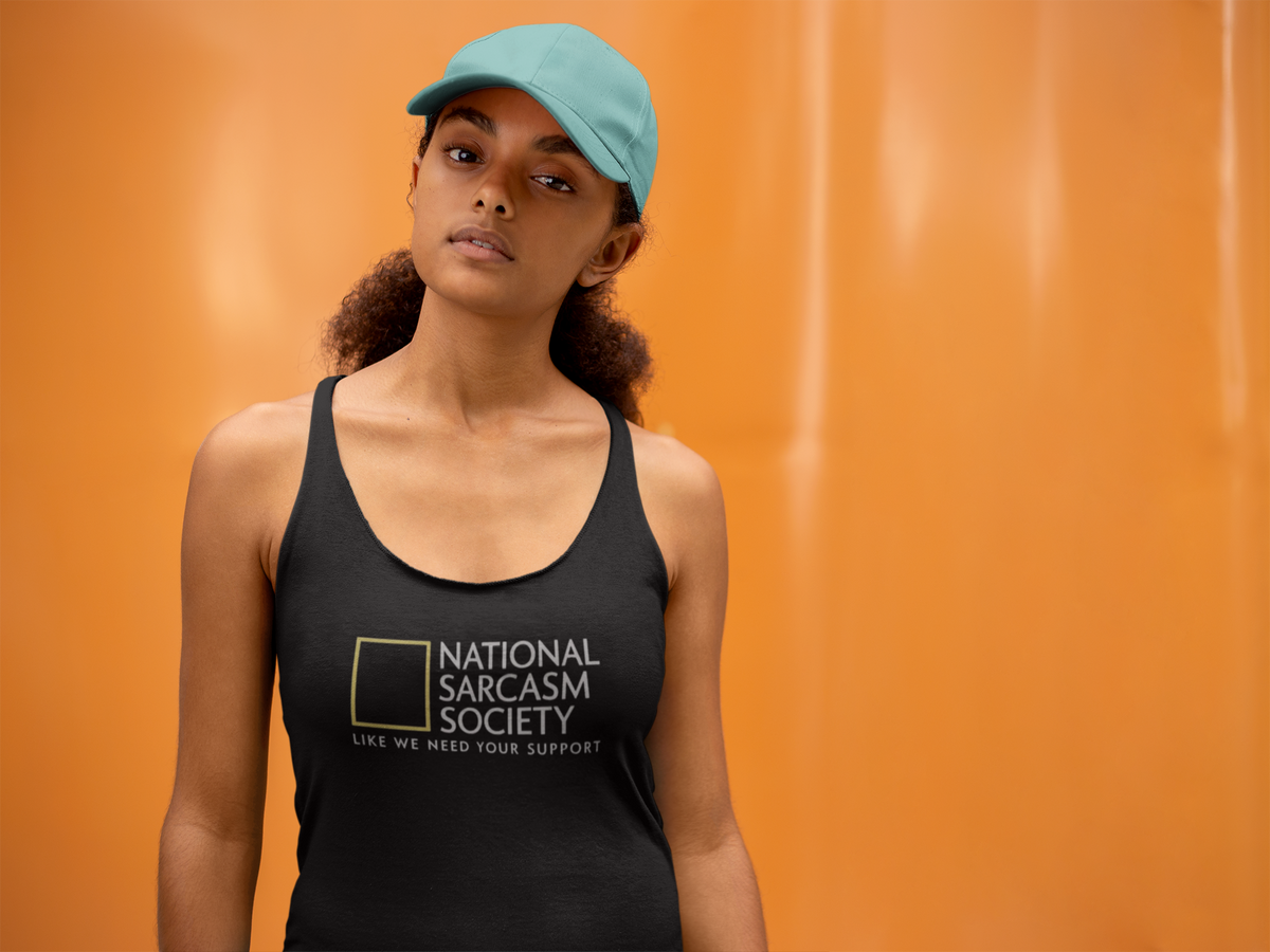 'National Sarcasm Society' racerback tank top in black, woman wearing it by an orange wall, Tank Top mockup, Geekpsters