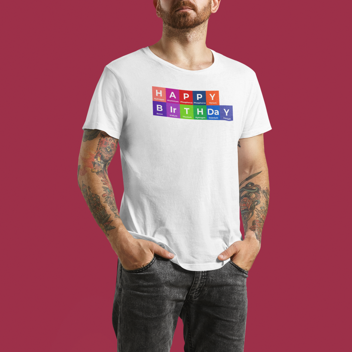'Happy Birthday' periodic table t-shirt in white, man wearing it on a red background, science pun gift