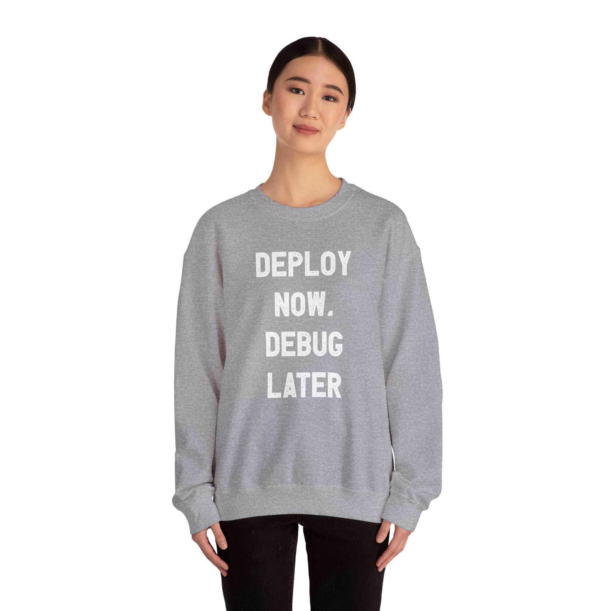 A tech enthusiast wears a "Deploy Now, Debug Later" sweatshirt in gray, perfectly capturing the vibe for the colder months ahead.