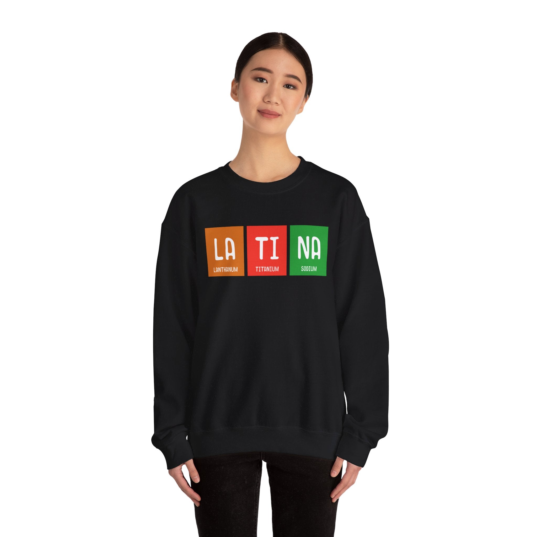 Person wearing a black LA-TI-NA - Sweatshirt with the word "LATINA" printed in colorful, periodic table-style blocks, showcasing a perfect blend of comfort and style as a winter essential.
