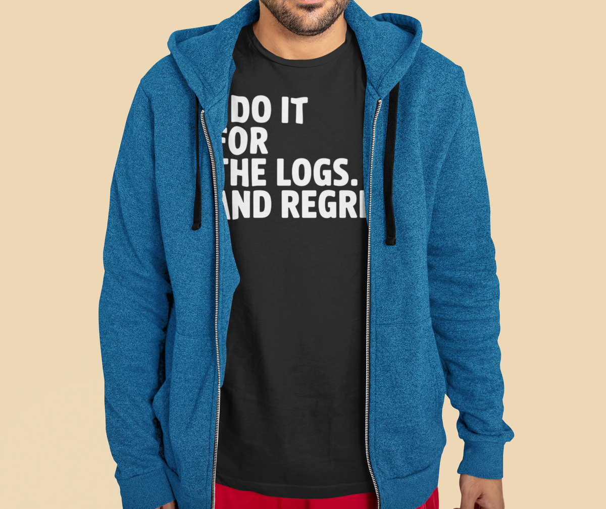 'I Do It For The Logs. And Regret.' t-shirt in black, man wearing it under a blue zip hoodie, funny programmer gift
