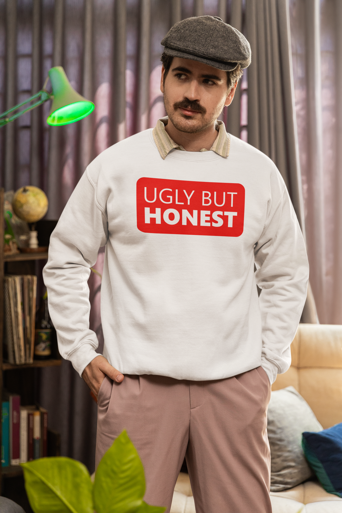 'Ugly But Honest' sweatshirt in heather grey, man wearing a flat cap indoors, sarcastic gift