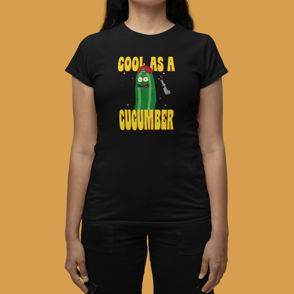 "Cool As A Cucumber" cartoon graphic tee in black, close-up on orange backdrop, funny pun gift for her