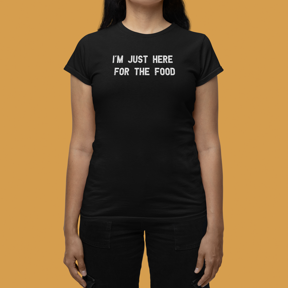 'I'm Just Here for the Food' t-shirt in black, woman wearing it in a stylish room, funny foodie graphic gift