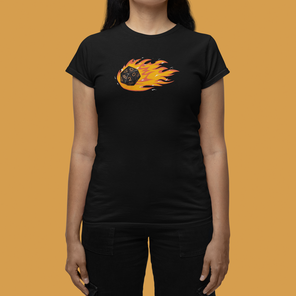"Polyhedral Dice On Fire" tee in black, woman wearing it on mustard background, funny gamer gift