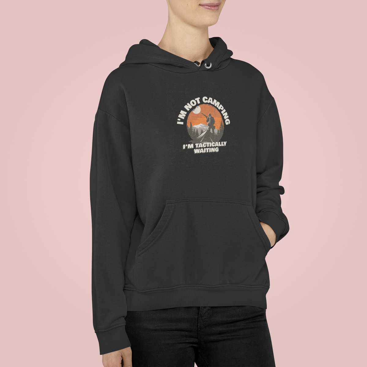 'I'm Not Camping' hiker graphic hoodie in black, woman wearing it, pink backdrop, camping gift idea