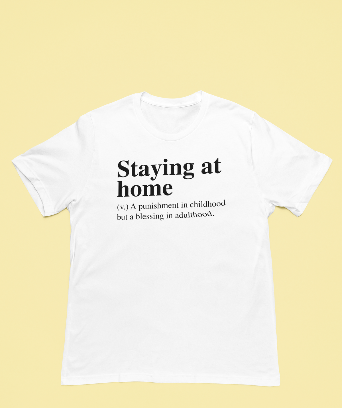 'Staying at Home' definition T-shirt in white, flat lay on pale yellow background, introvert humor tee
