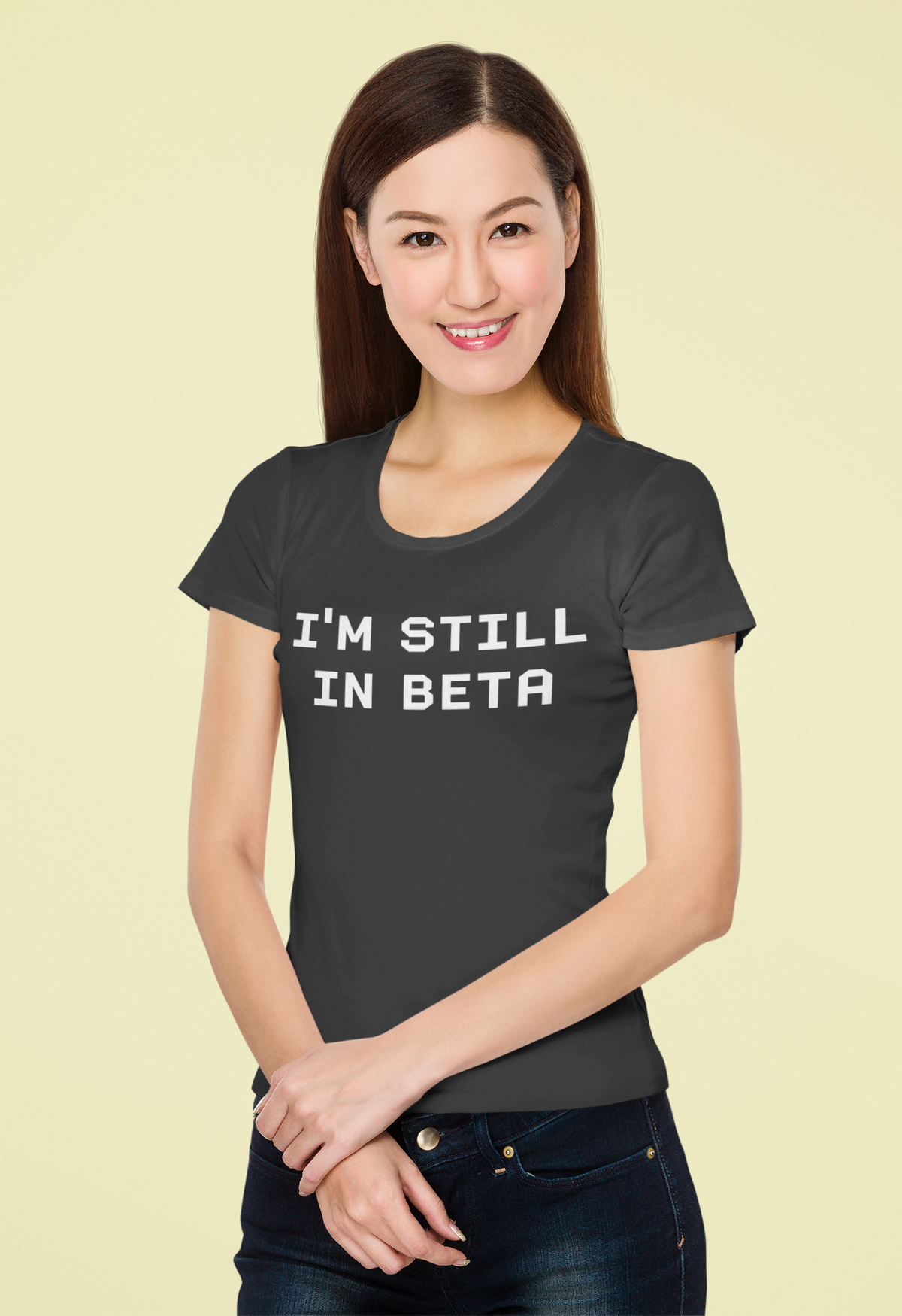 "I'm Still In Beta" typography t-shirt in black, woman wearing it on yellow background, funny gift for coders