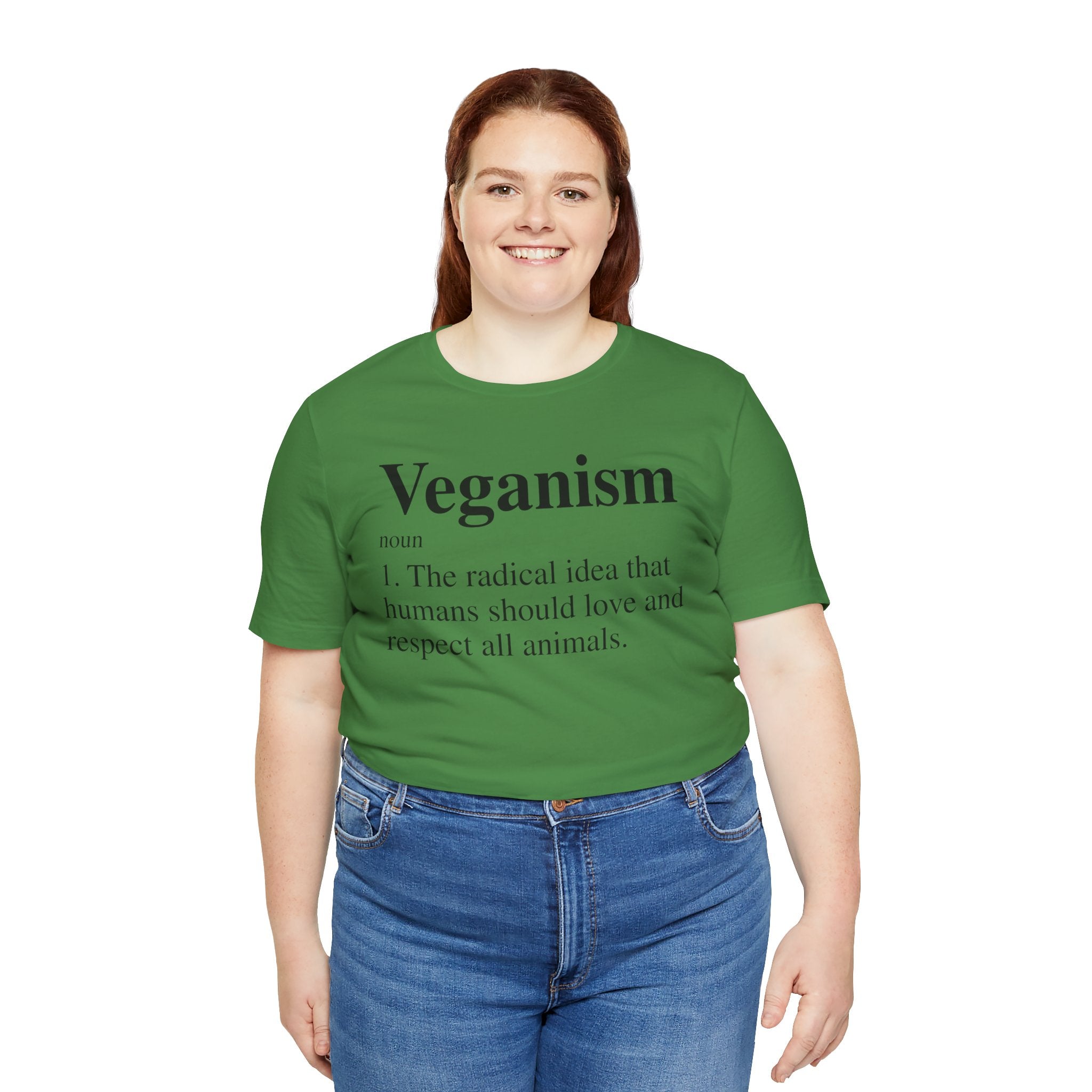 A woman with brown hair smiling in a Green Unisex Veganism T-Shirt, paired with blue jeans.