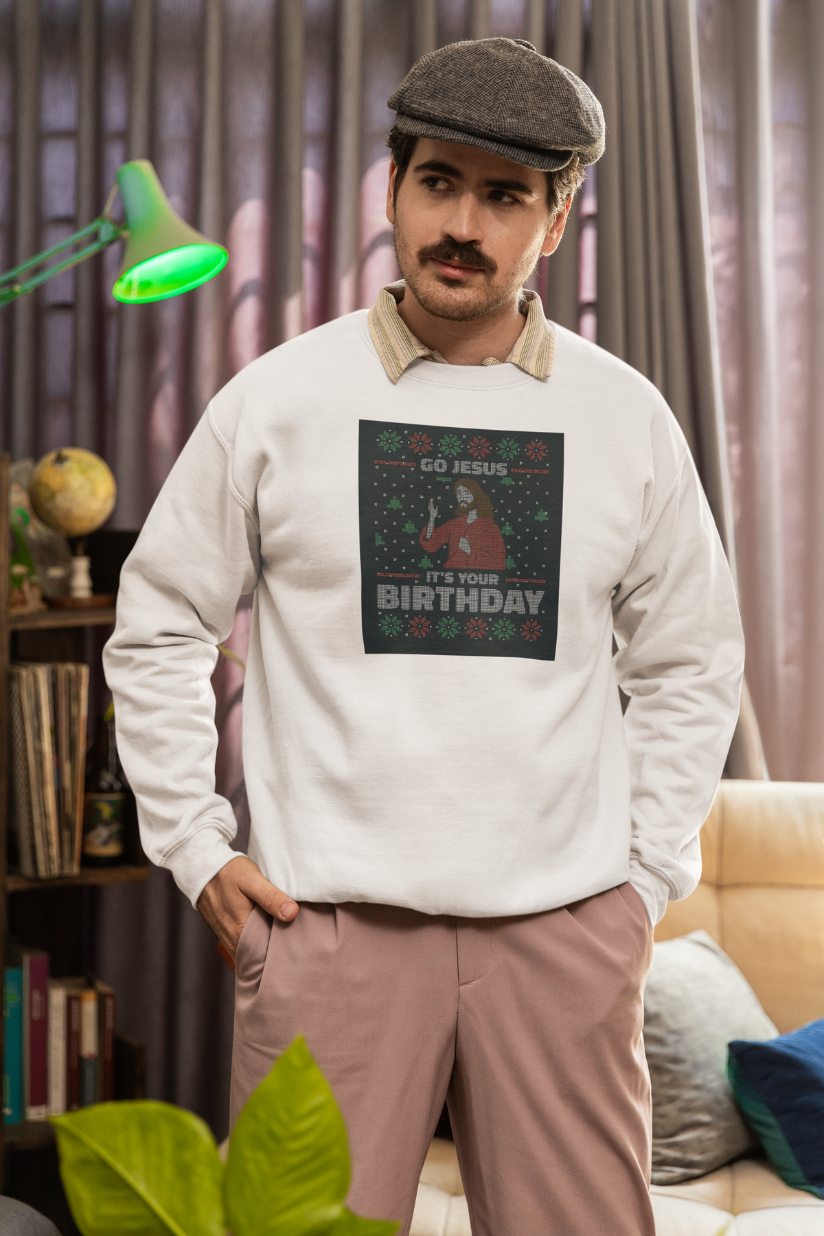 'Go Jesus It's Your Birthday Ugly Sweater Sweatshirt' in white, man in a cozy living room, Sweatshirt mockup, Geekpsters