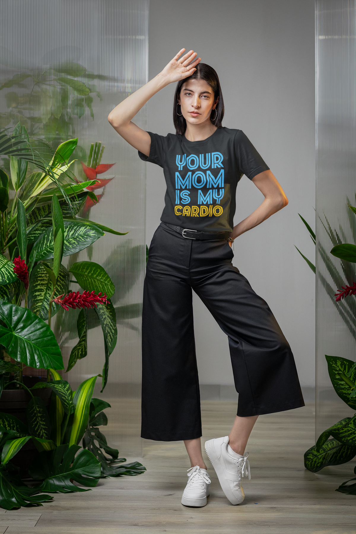'Your Mom Is My Cardio' tee in black, woman wearing it among plants, funny sarcastic gift for coworkers