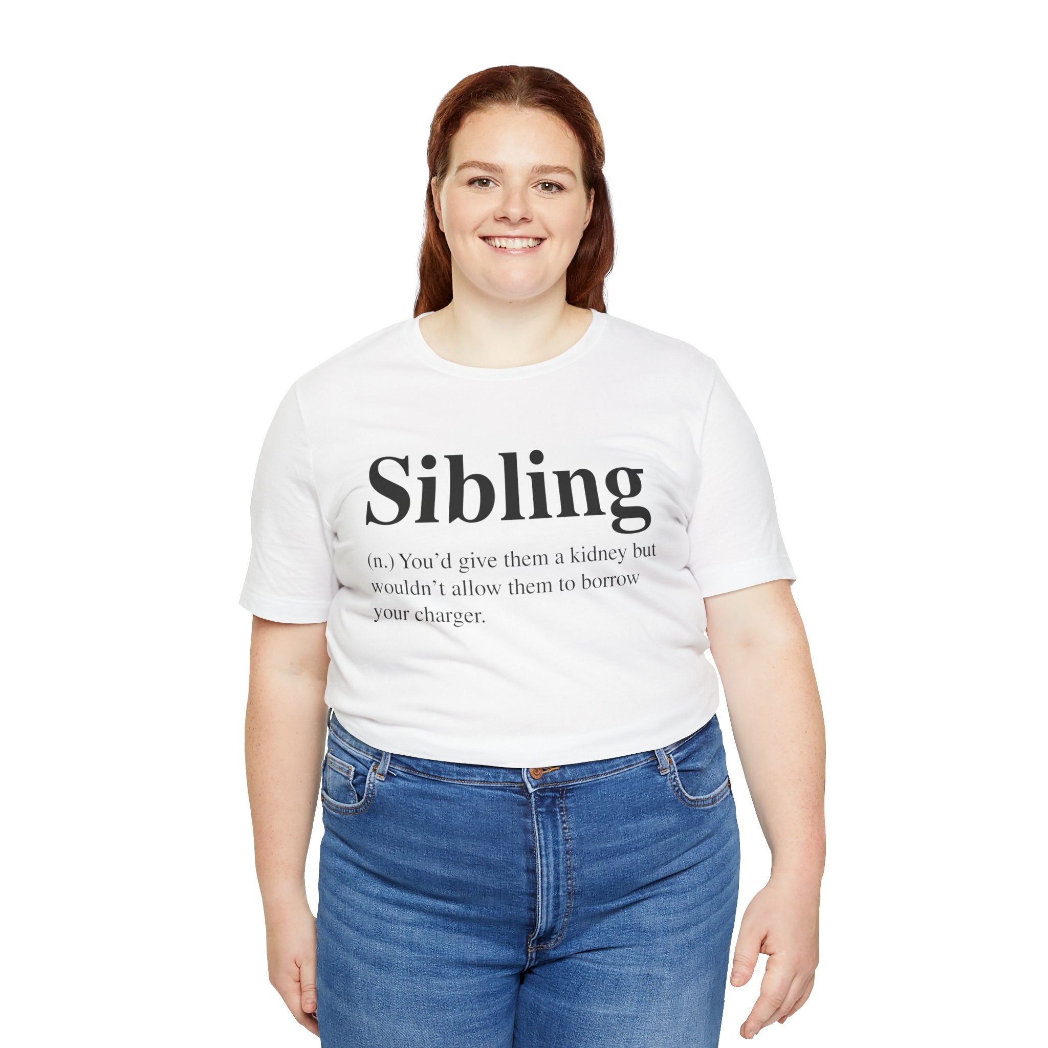 A woman in a white soft cotton Sibling T-Shirt with the word "siblings" and its humorous definition printed on it, paired with blue jeans, smiling at the camera.