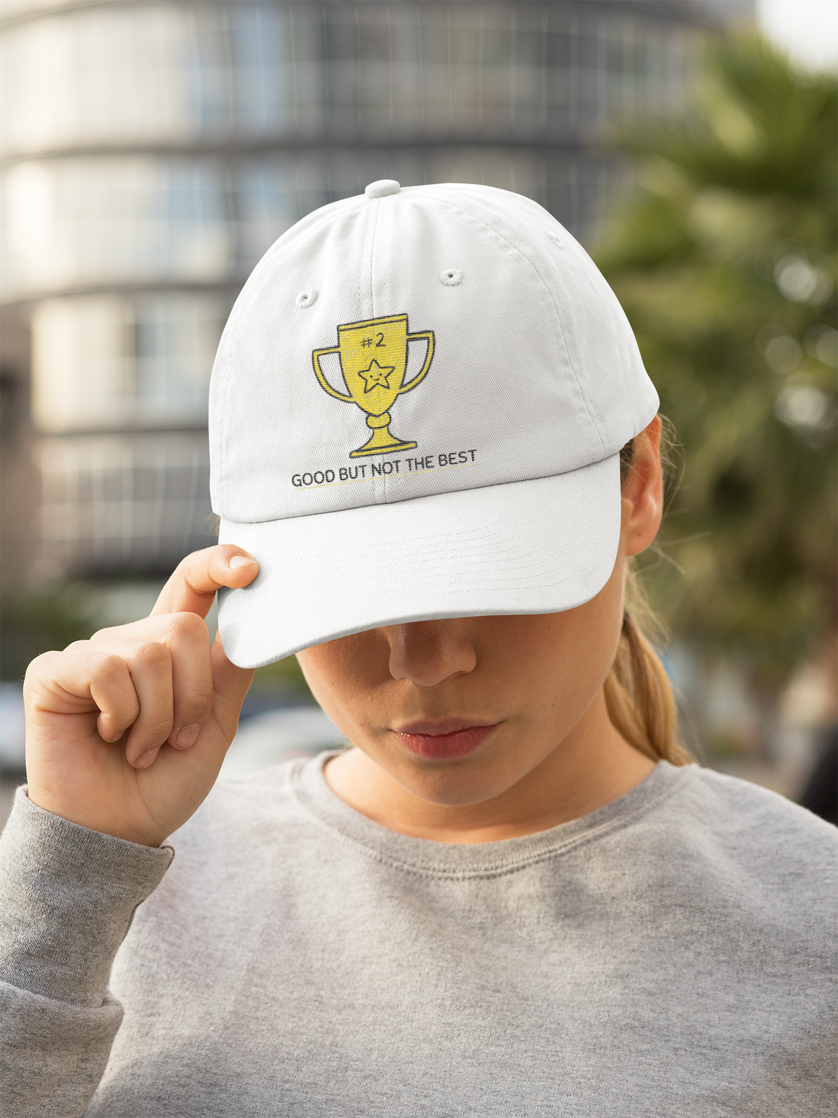 'Good But Not the Best' trophy dad hat in white, woman wearing it outdoors, funny embroidered cap gift