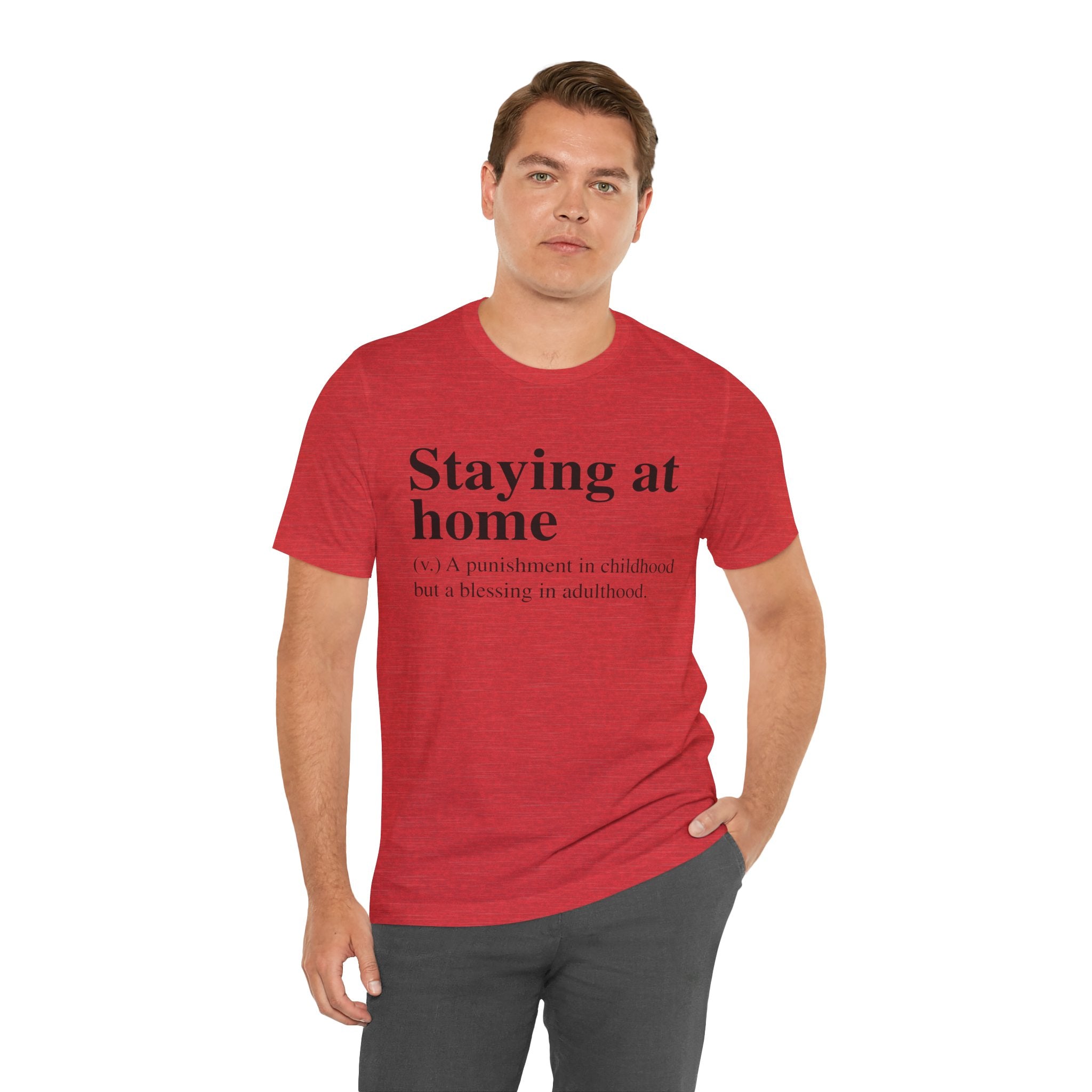 Man in a red Staying at Home T-Shirt with text "staying home - (n) a punishment in childhood but a blessing in adulthood" standing with one hand on his hip.