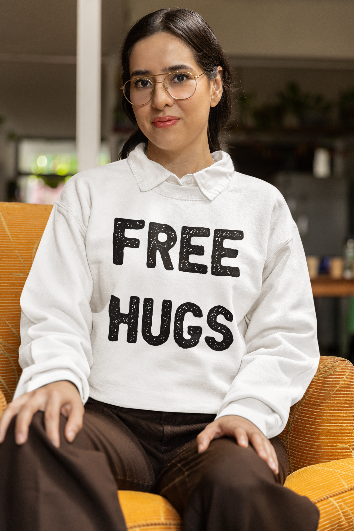 'Free Hugs' sweatshirt in white, woman wearing it seated indoors, funny sarcastic gift idea
