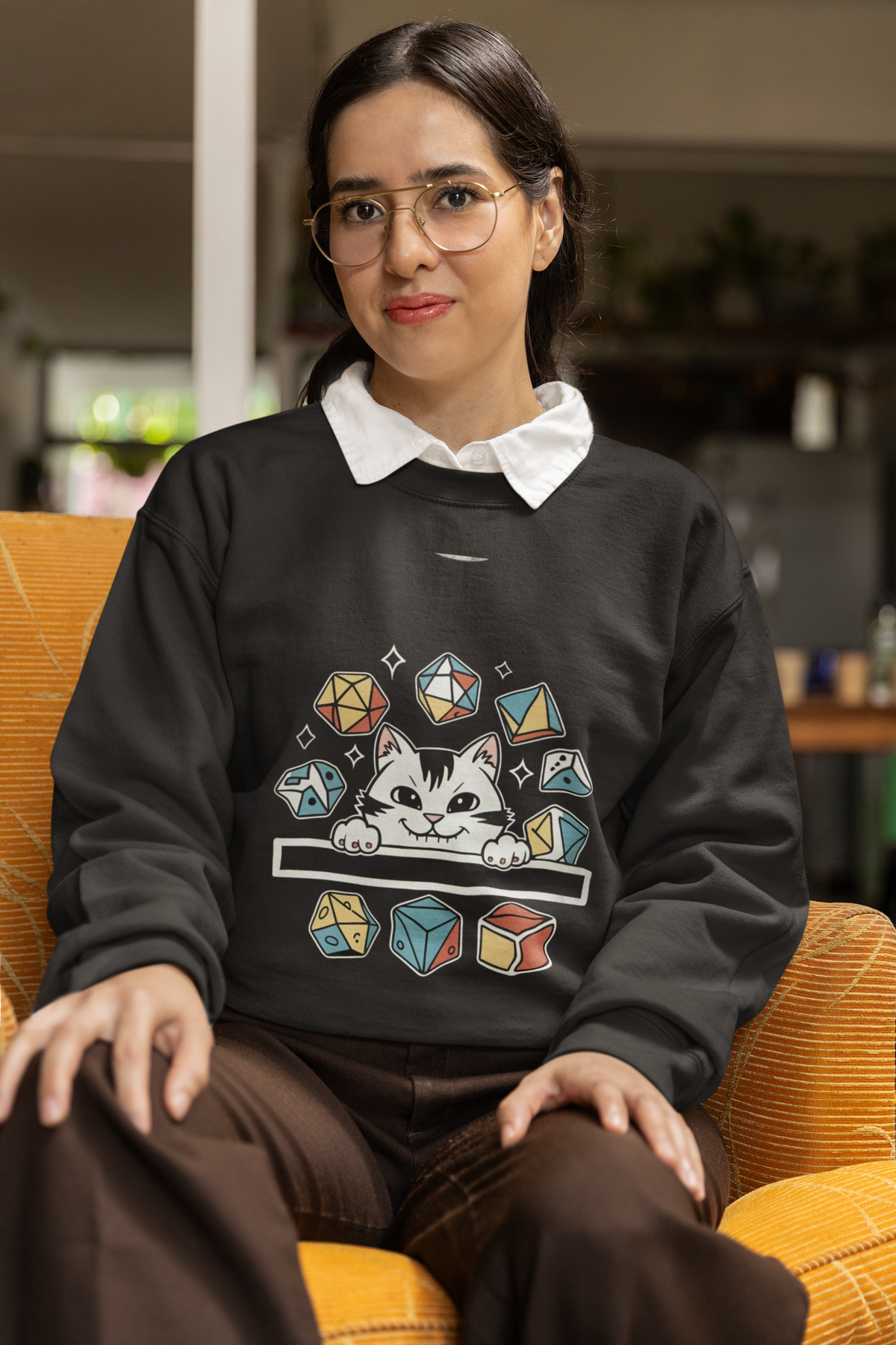 'Cat Dice' sweatshirt in black, woman wearing it seated indoors, funny tabletop RPG crewneck sweatshirt gift