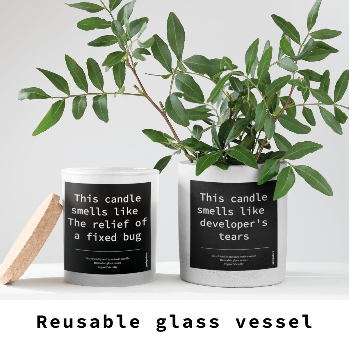 Two This Candle Smells Like a Heated Debate About Code Style- Scented Soy Candles in reusable glass jars with humorous labels, accompanied by a green plant branch and a wooden item on a grey background.