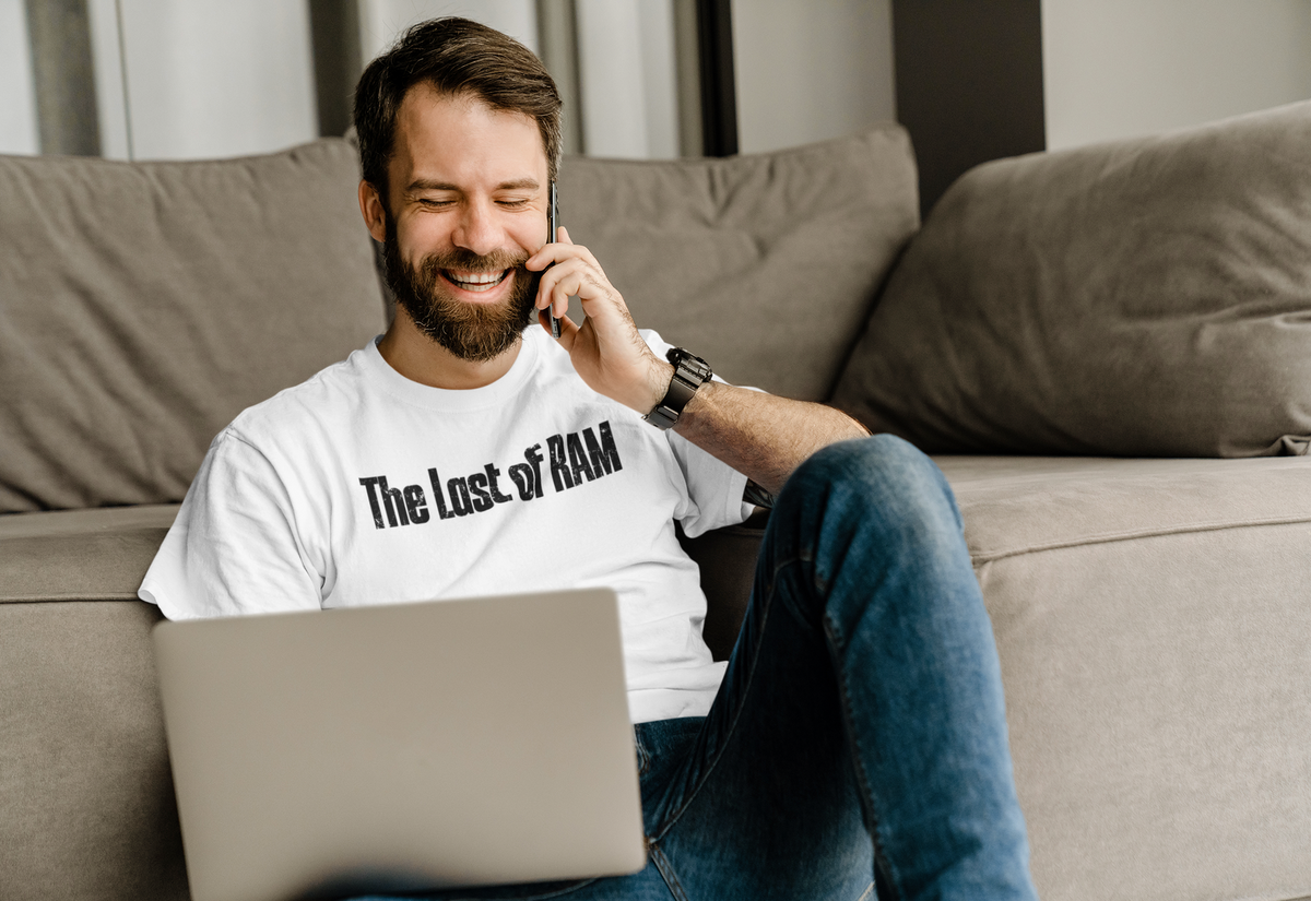 'The Last of RAM' T-shirt in white, man on the phone wearing it on a couch, funny gamer gift tee