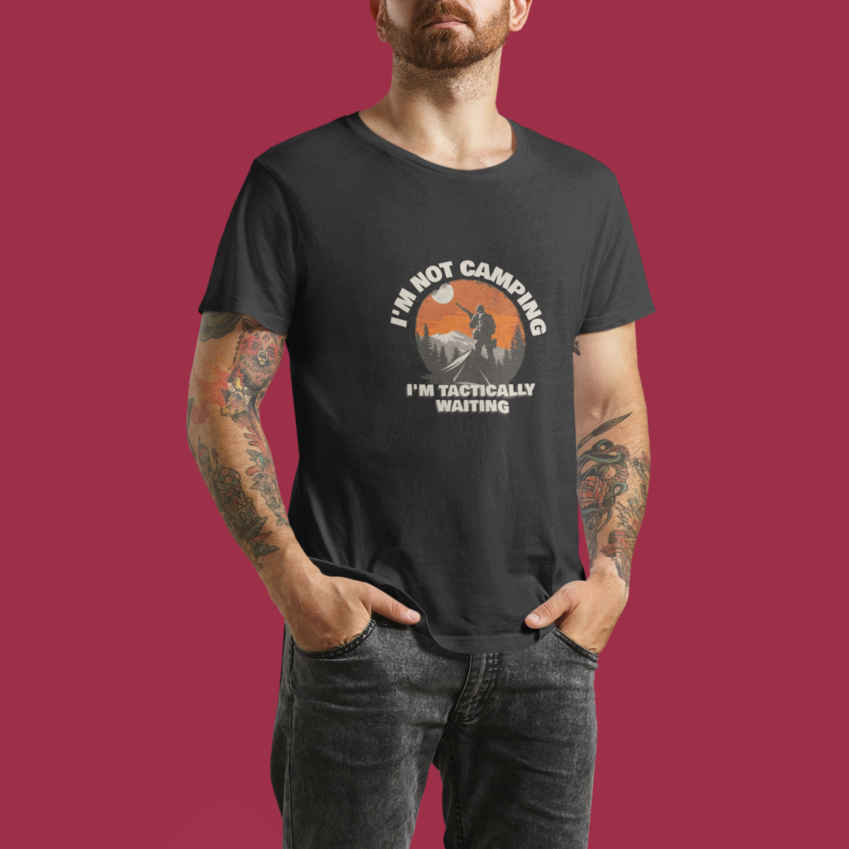 'I'm Not Camping' hiker graphic t-shirt in charcoal, man wearing it, maroon backdrop, camping gift
