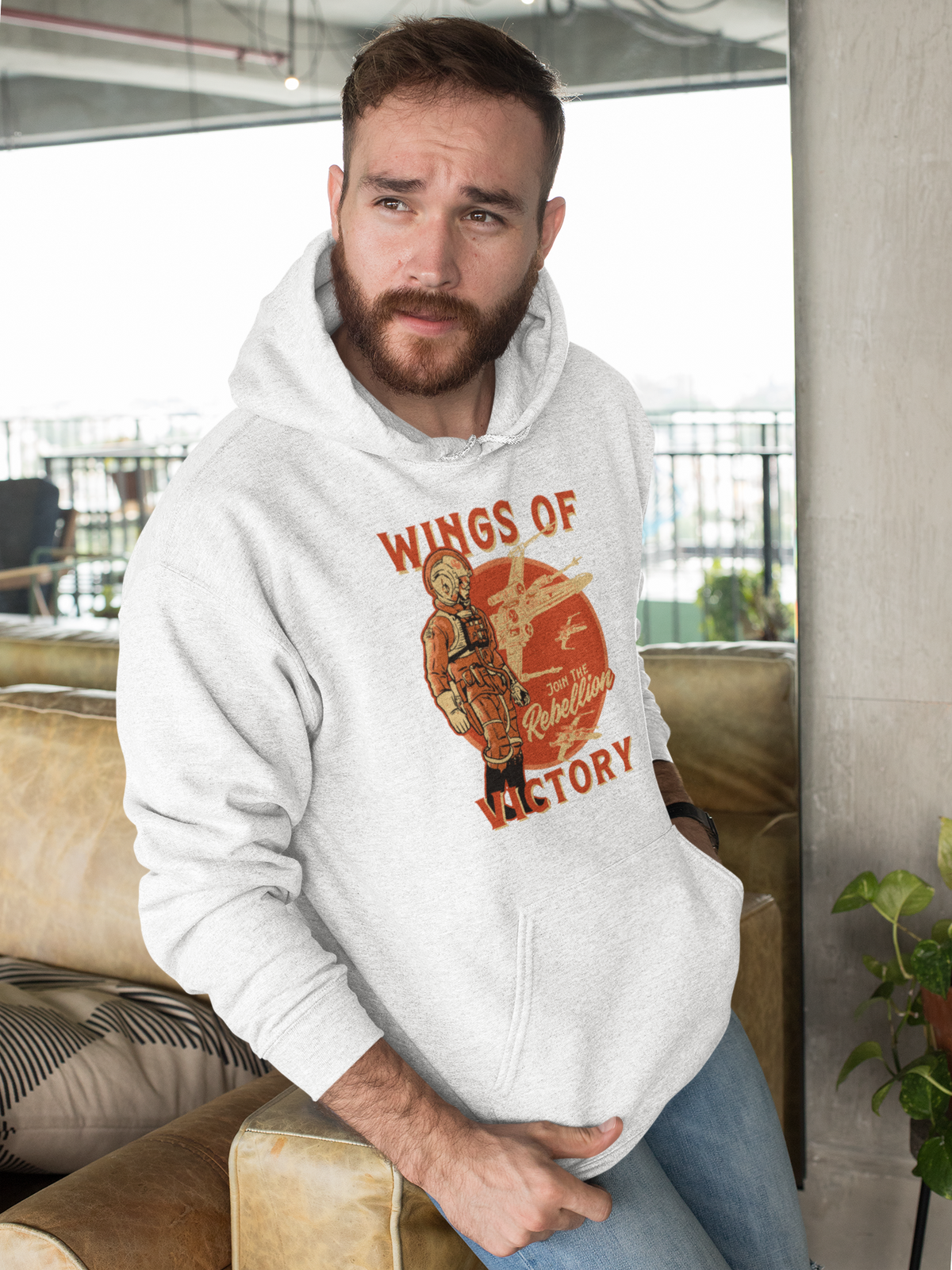 'Wings of Victory' hoodie in heather gray, bearded man wearing it indoors, rebel warrior hoodie gift