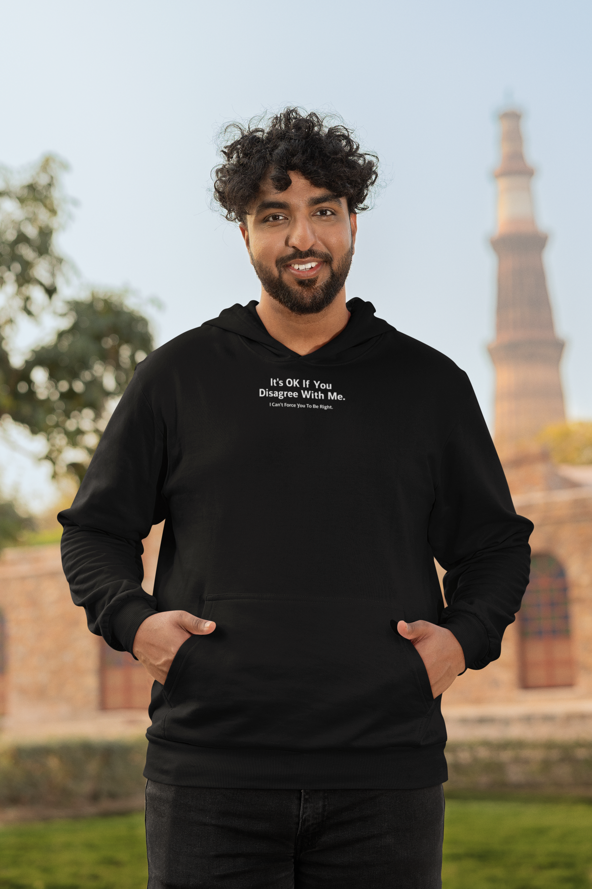 'It's Ok If You Disagree Hoodie' in black, man by a historic building, Hoodie mockup, Geekpsters