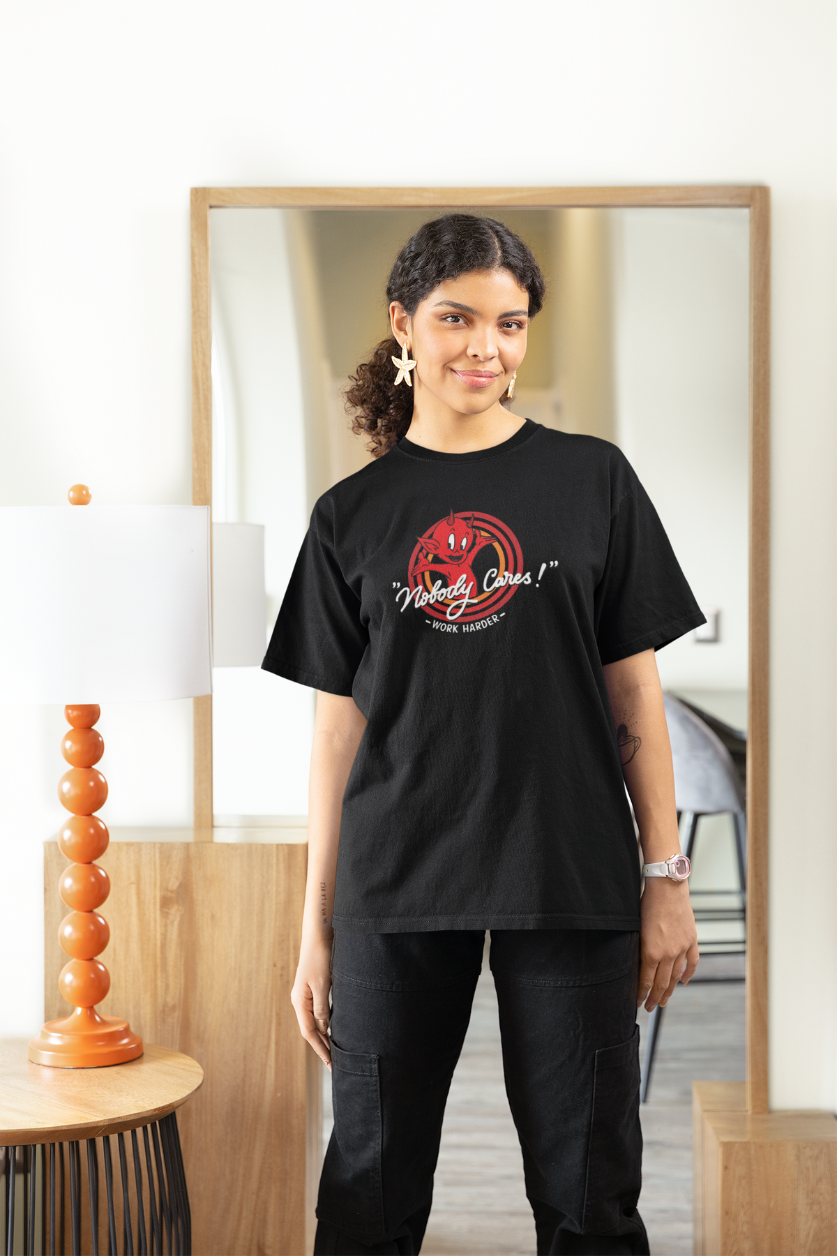 "Nobody Cares, Work Harder" devil graphic tee in black, woman wearing it at home, funny motivational gift