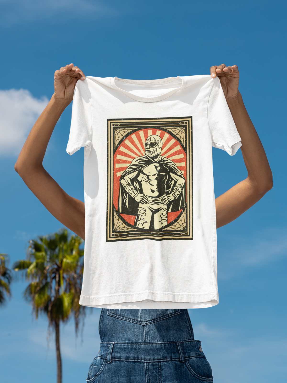 'Mexican Wrestler' t-shirt in white, man holding it up outdoors under palm trees, funny lucha libre gift