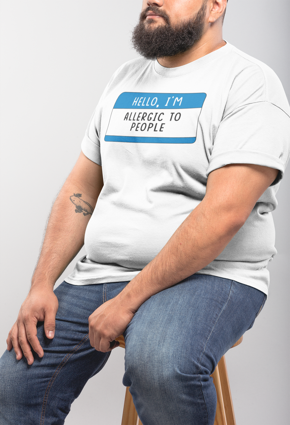 Hello I'm Allergic to People T-shirt in white, man sitting sideways, casual funny sarcastic tee