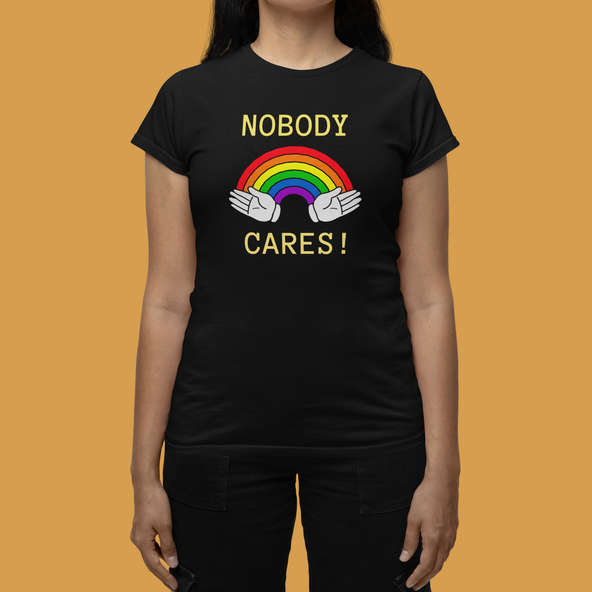 "Nobody Cares" rainbow women's tee in black, flat lay on orange background, funny sarcastic gift shirt