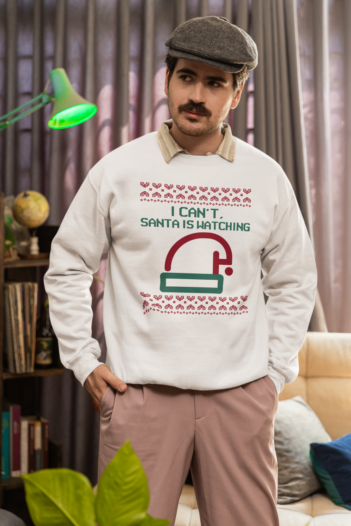 'I Can't Santa Is Watching' camera graphic sweatshirt in white, man wearing flat cap indoors, funny Christmas gift