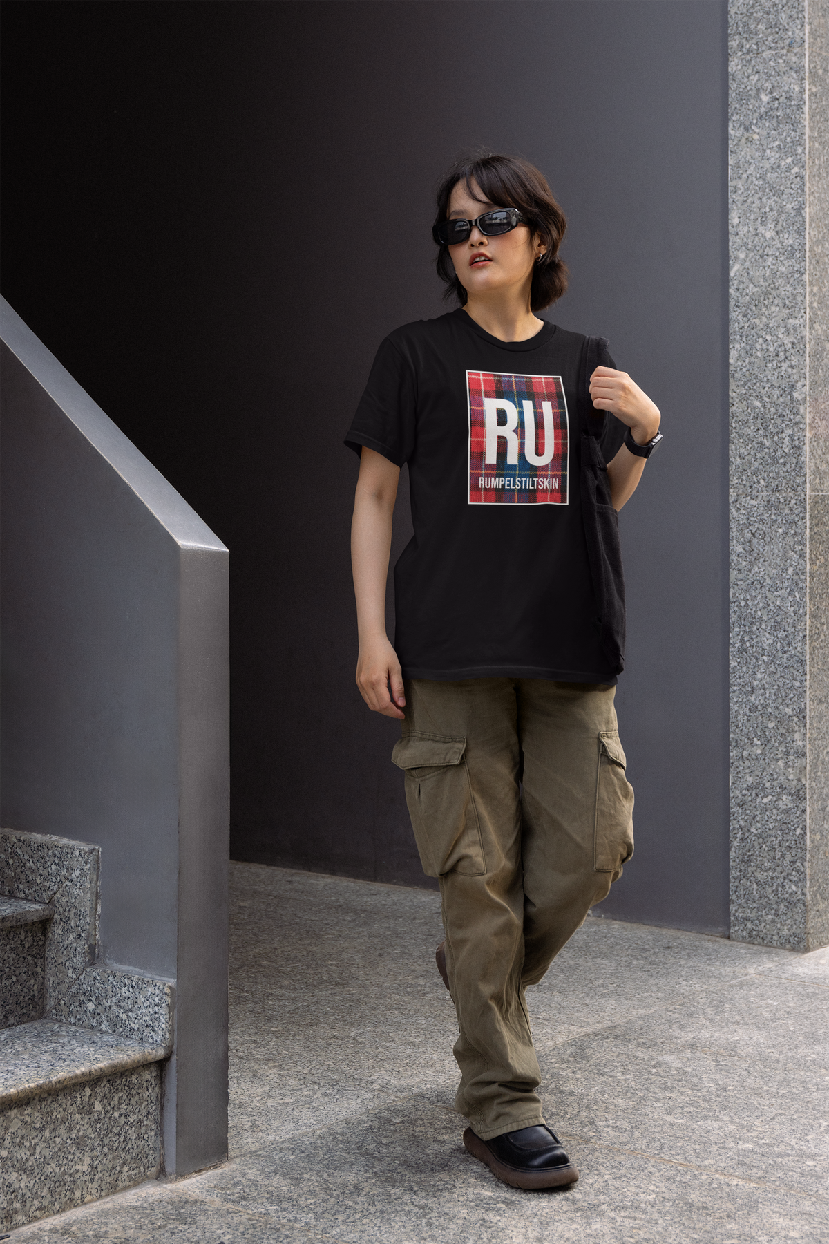 'RU Rumpelstiltskin' periodic table women's tee in black, woman walking outdoors, casual streetwear photo