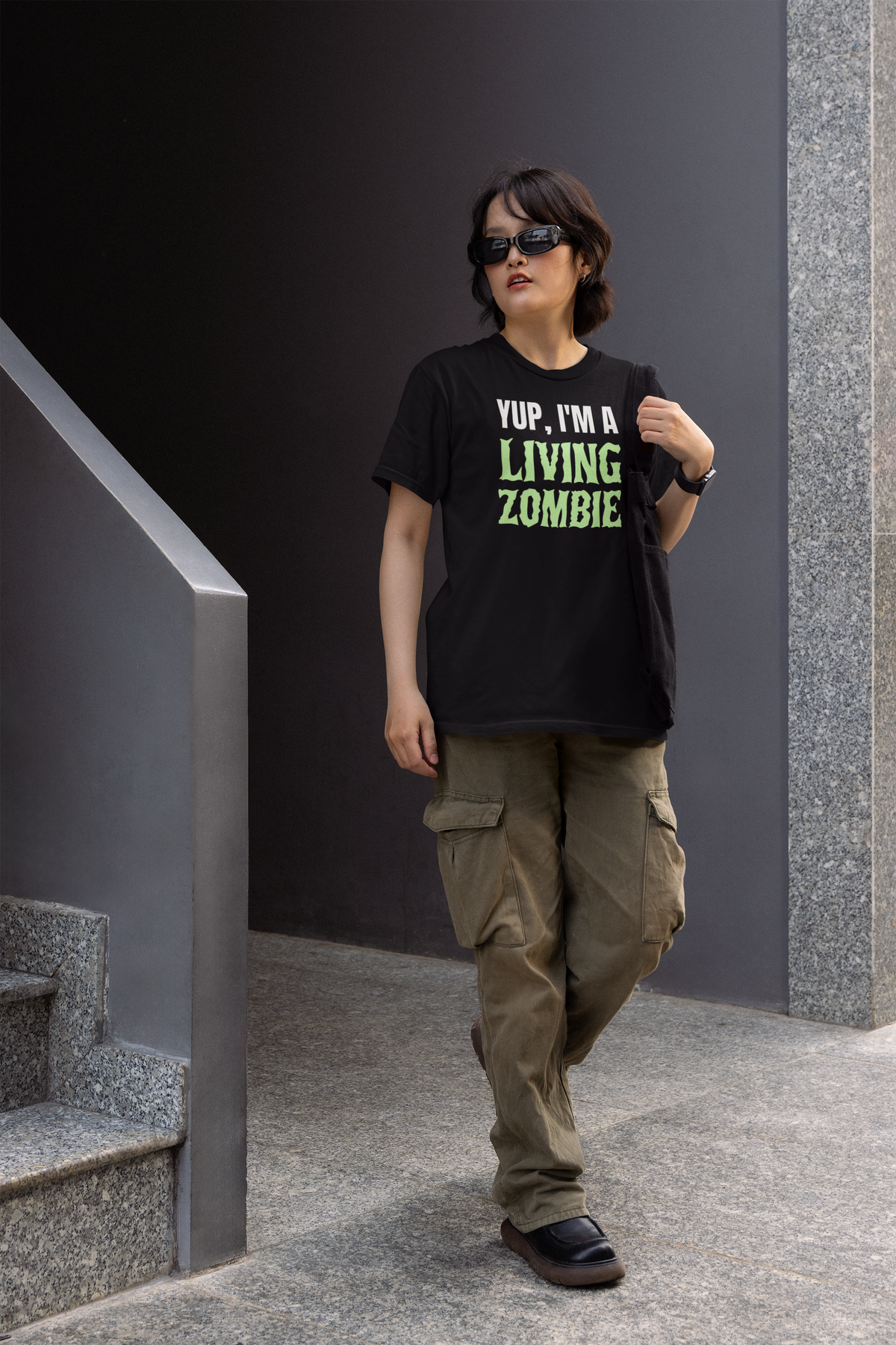 'Yup, I'm a Living Zombie' women's tee in black, woman wearing it outdoors, funny zombie gift for her