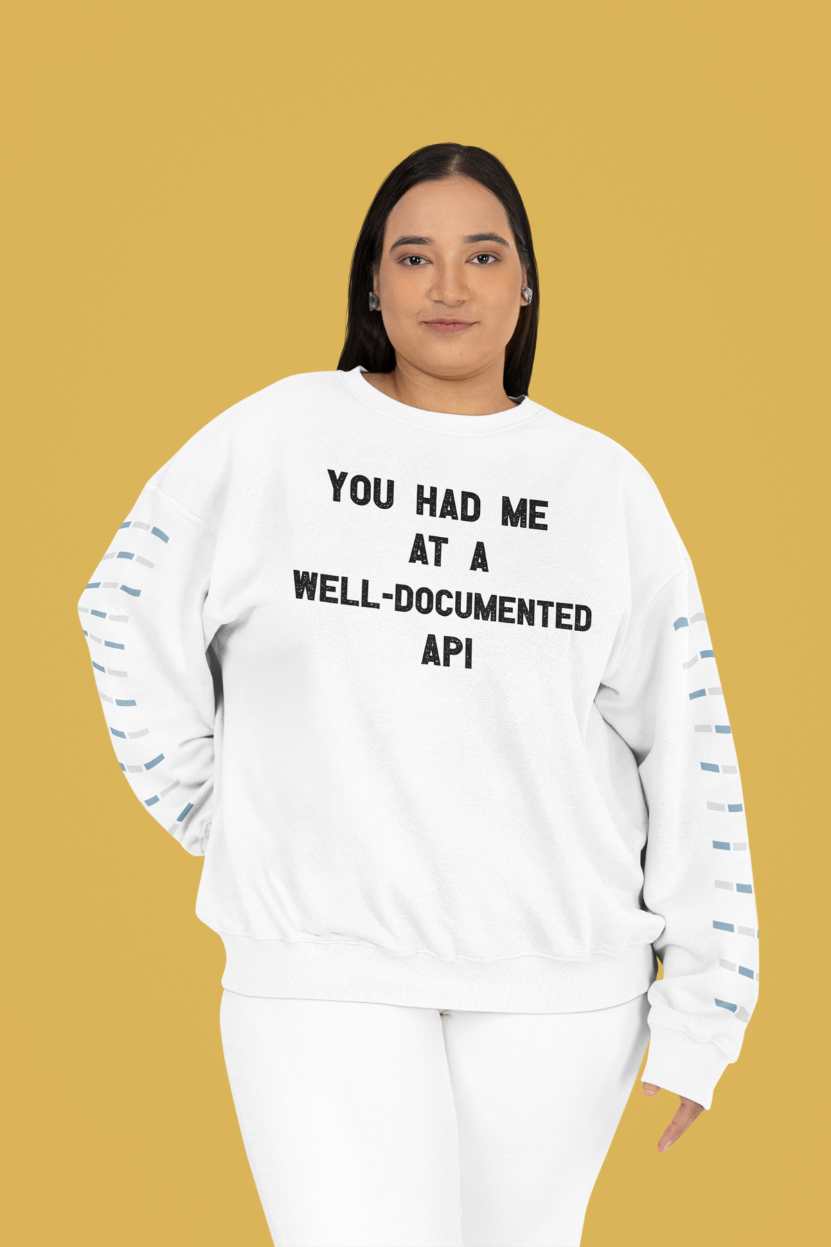 "You Had Me At A Well-Documented API" sweatshirt in white, curvy woman wearing it on yellow backdrop, coder gift