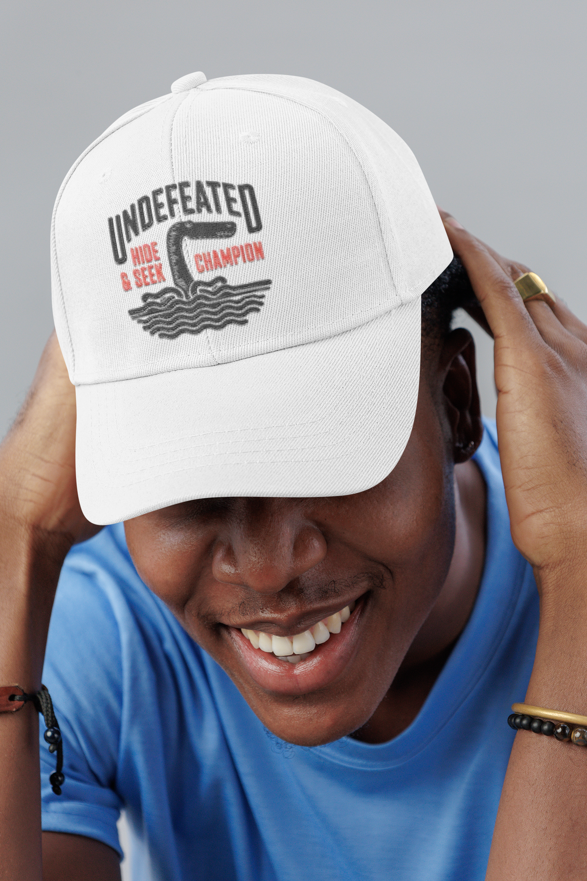 Undefeated Hide and Seek Bigfoot dad hat, smiling man in a studio, lifestyle mockup, Geekpsters