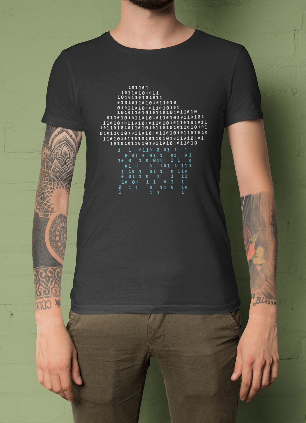 'It's Raining Code' cloud binary t-shirt in black, tattooed man model wearing it against a green background, coder gift