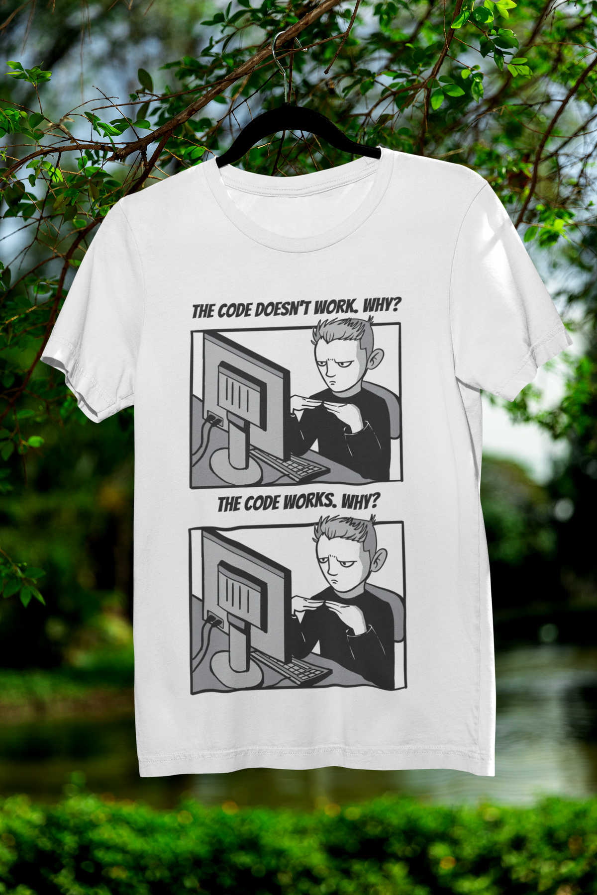 'The Code Doesn't Work, Why?' t-shirt in white, hanging outdoors among green trees, funny programmer joke tee
