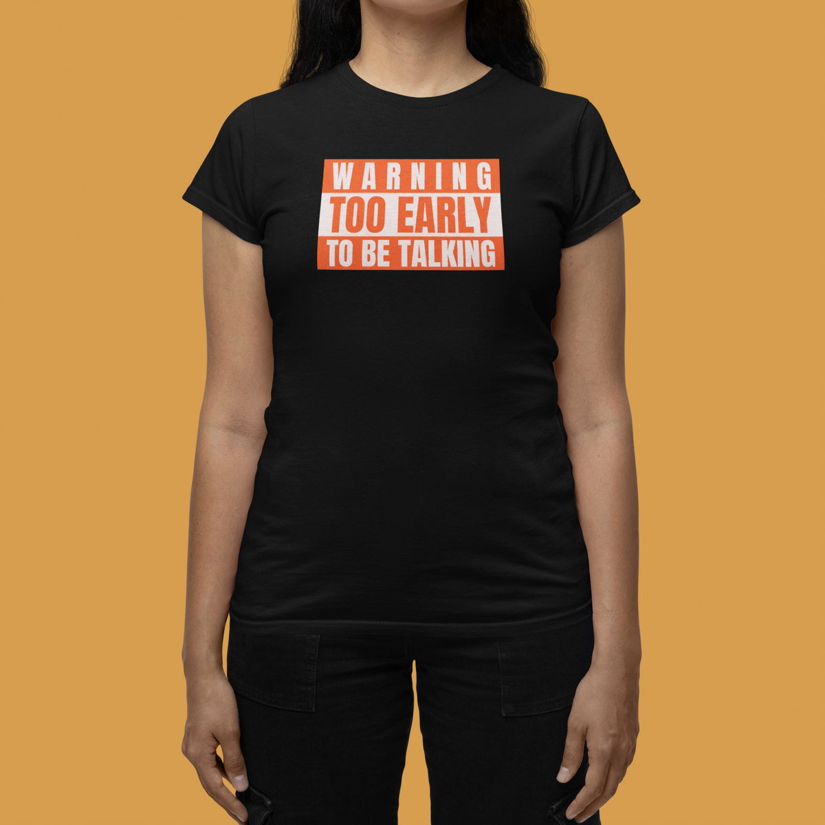'Warning Too Early To Be Talking' t-shirt in black, woman wearing it orange background, funny gift