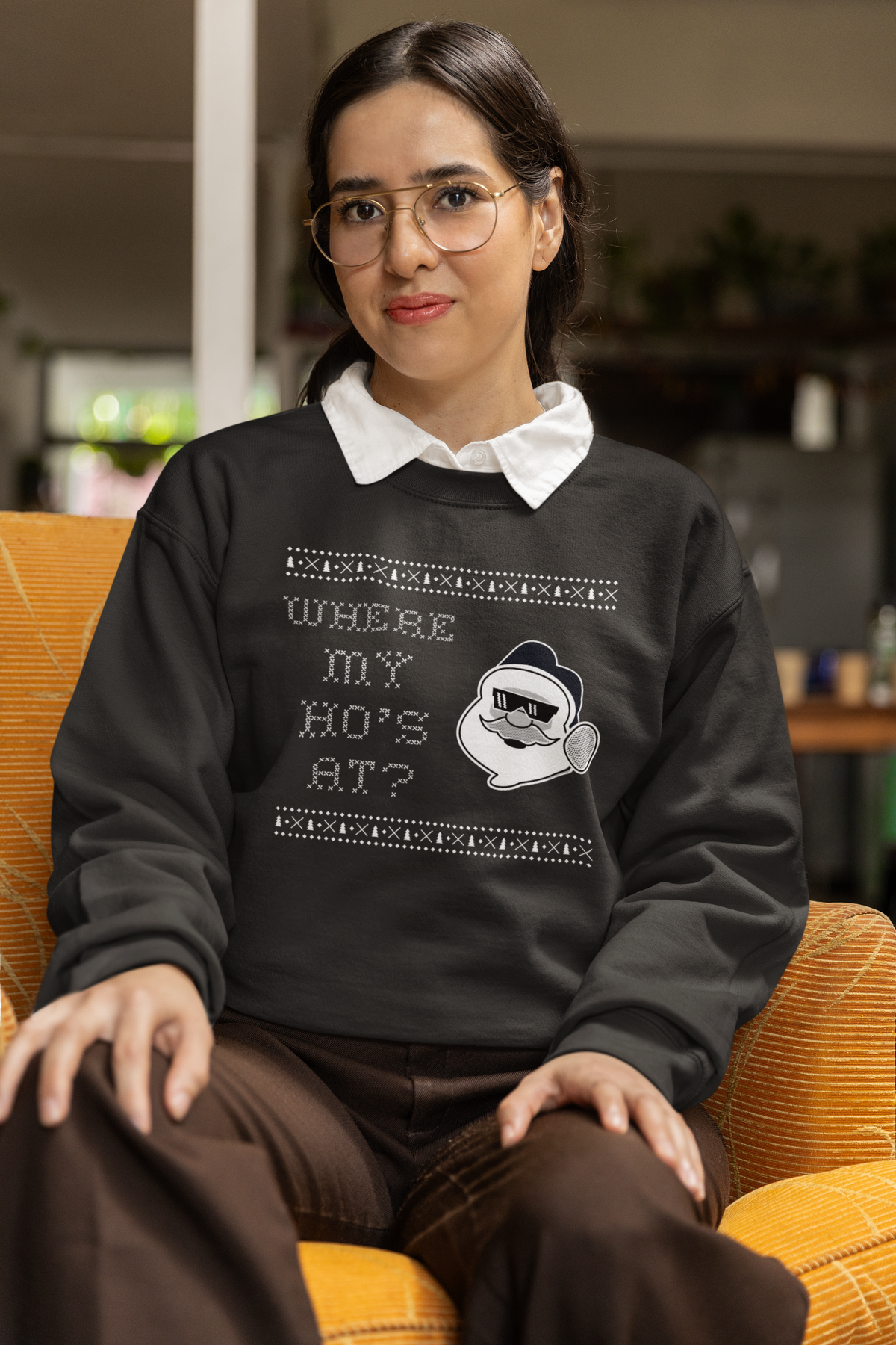 'Where My Ho's At' Santa graphic sweatshirt in black, woman wearing it seated indoors, funny Christmas gift