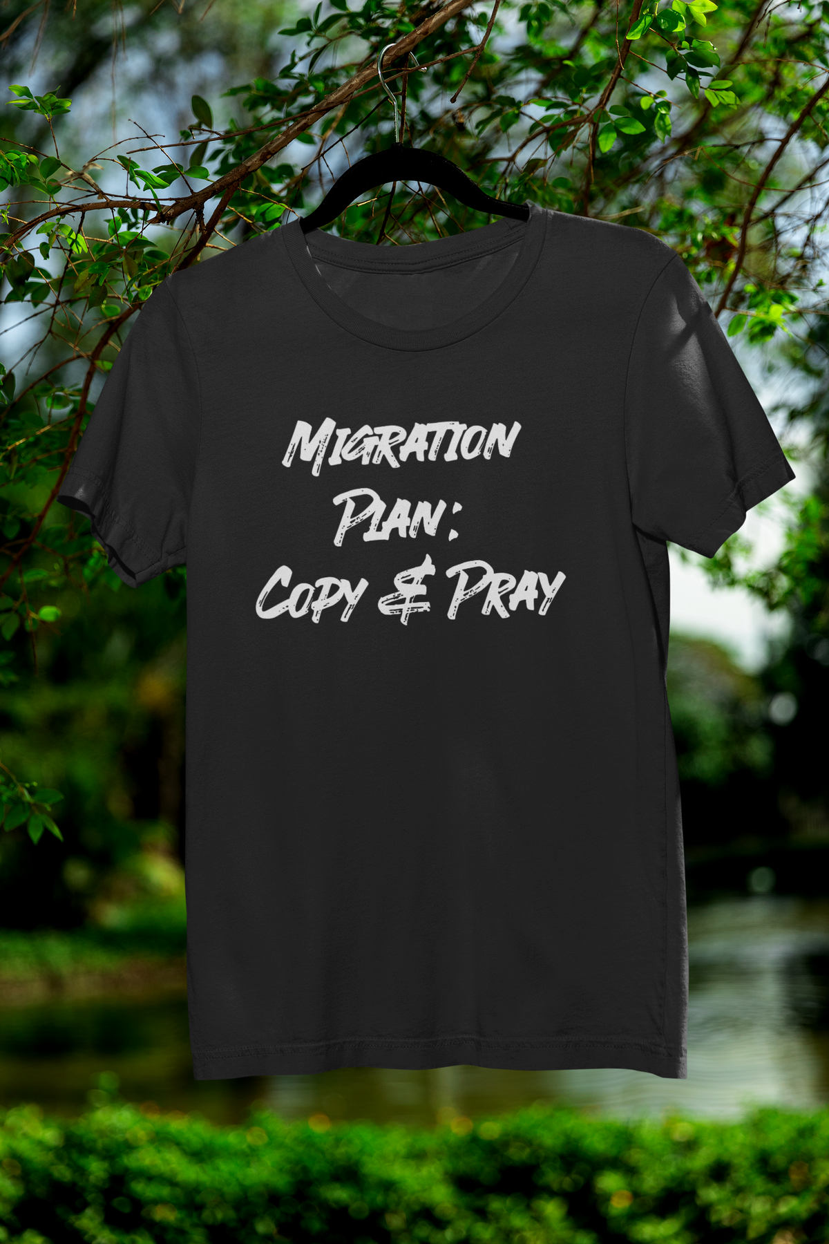 'Migration Plan: Copy and Pray' t-shirt in black, hanging outdoors on a tree branch, funny sysadmin gift