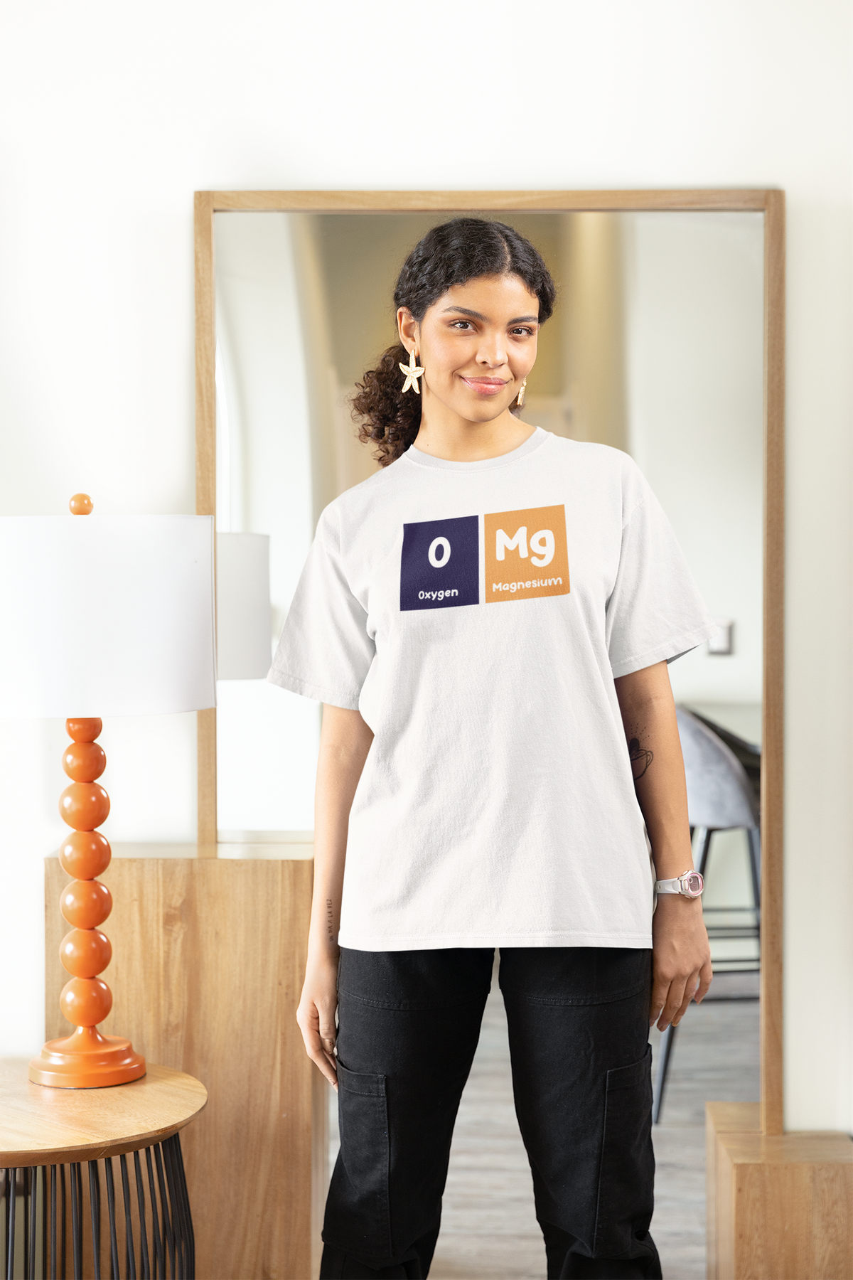 'O-Mg' periodic table women's tee in white, woman standing at home, casual lifestyle photo